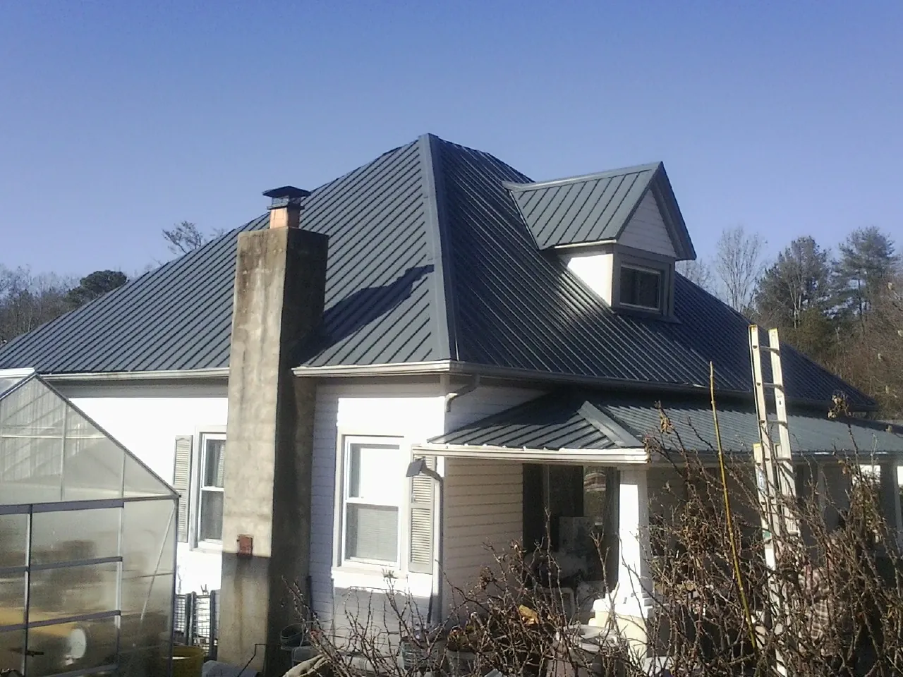 Dark blue standing seam metal roof on a white farmhouse with dormer — Slate & Tile Roof Repair by Roofing Brothers in Red Bluff