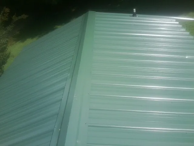 New green metal panels meeting at the ridge of a roof — Flat Roof Repair work by our crew in Red Bluff