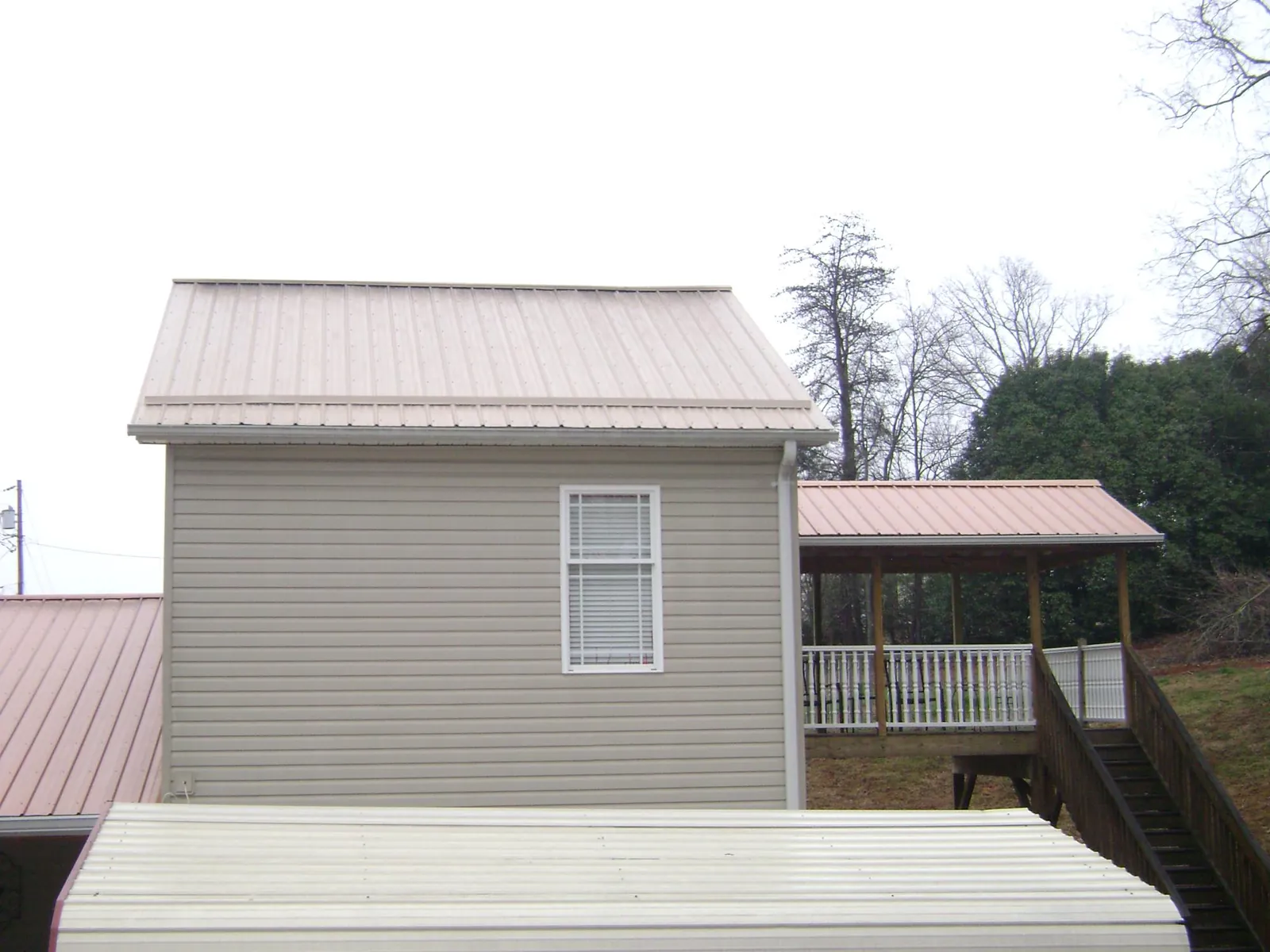Tan metal roofs on a two story addition and attached porch, from a Roof Replacement job in Red Bluff