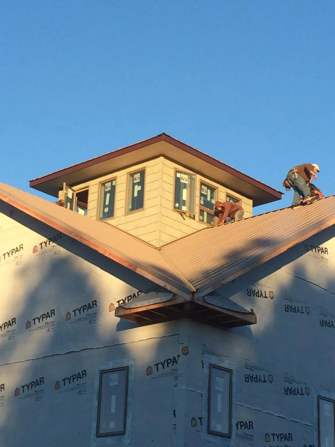 Roofers working around a rooftop cupola on a new metal roof at sunset — Roof Waterproofing in Red Bluff by Roofing Brothers